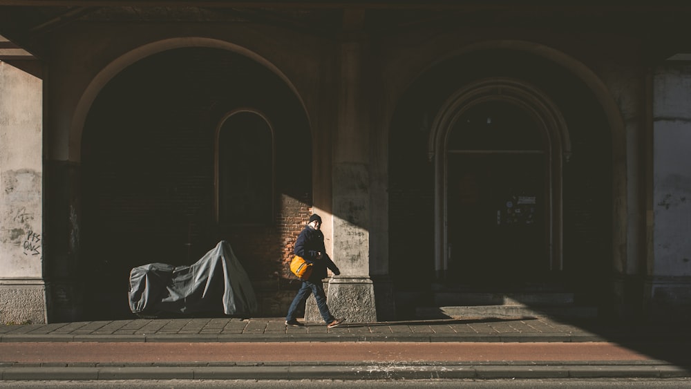 a man walking down a street next to a building