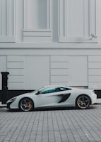 white and black coupe beside white building paint