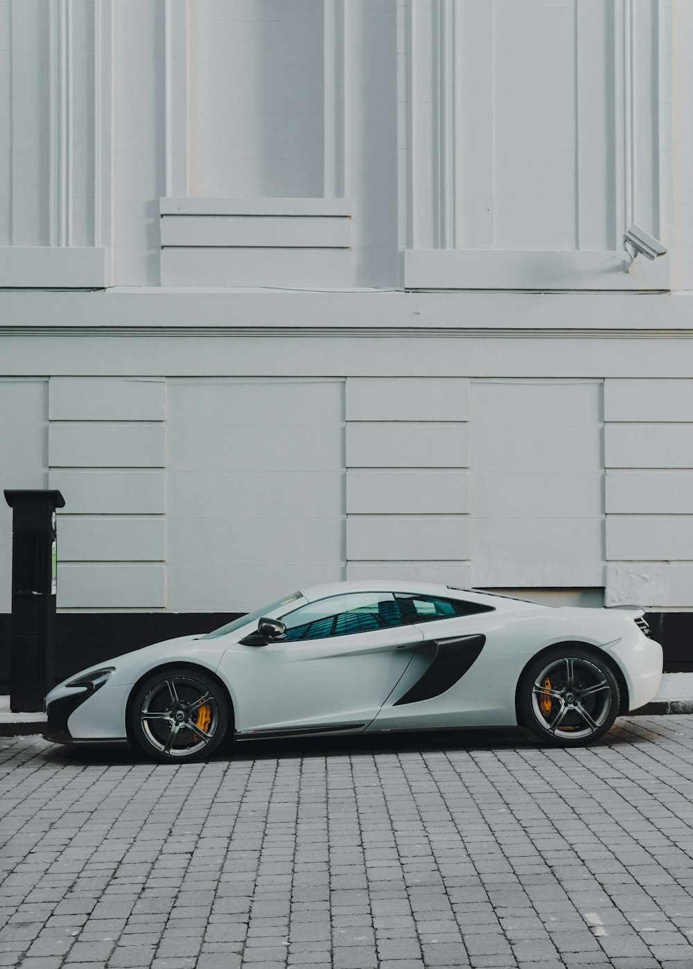 white and black coupe beside white building paint