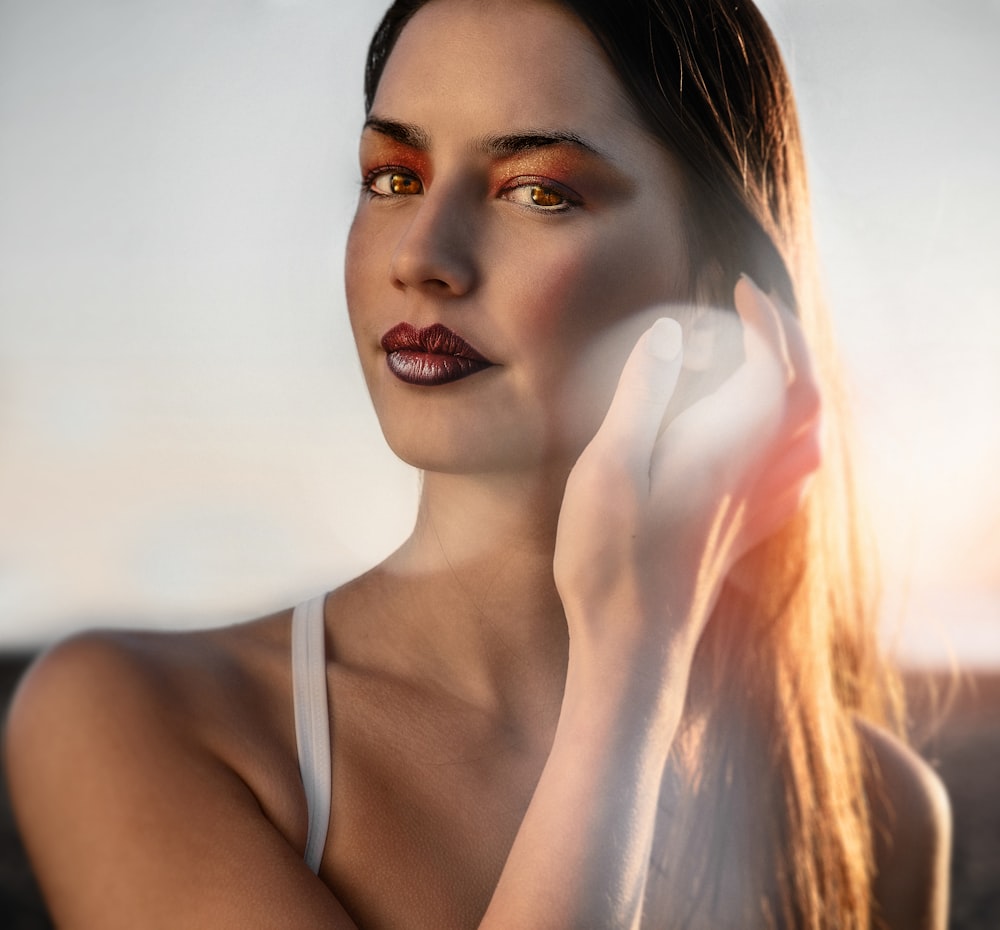 woman's face holding her hair during daytime