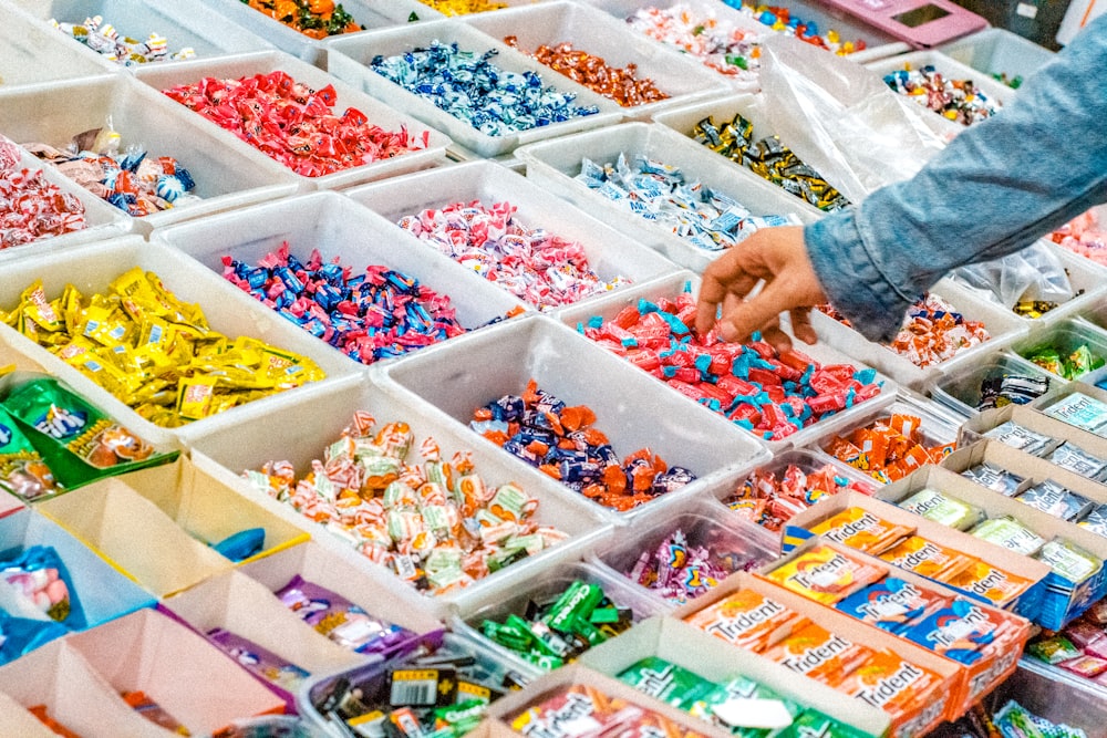 Persona sosteniendo un paquete de dulces en una caja de plástico blanca