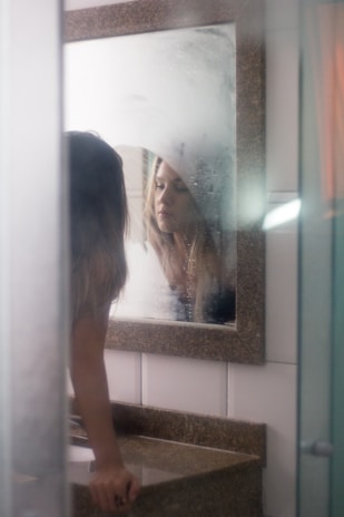 A close-up of a college girl’s relaxed expression as she leans back on a bathroom sink, capturing an intimate moment.