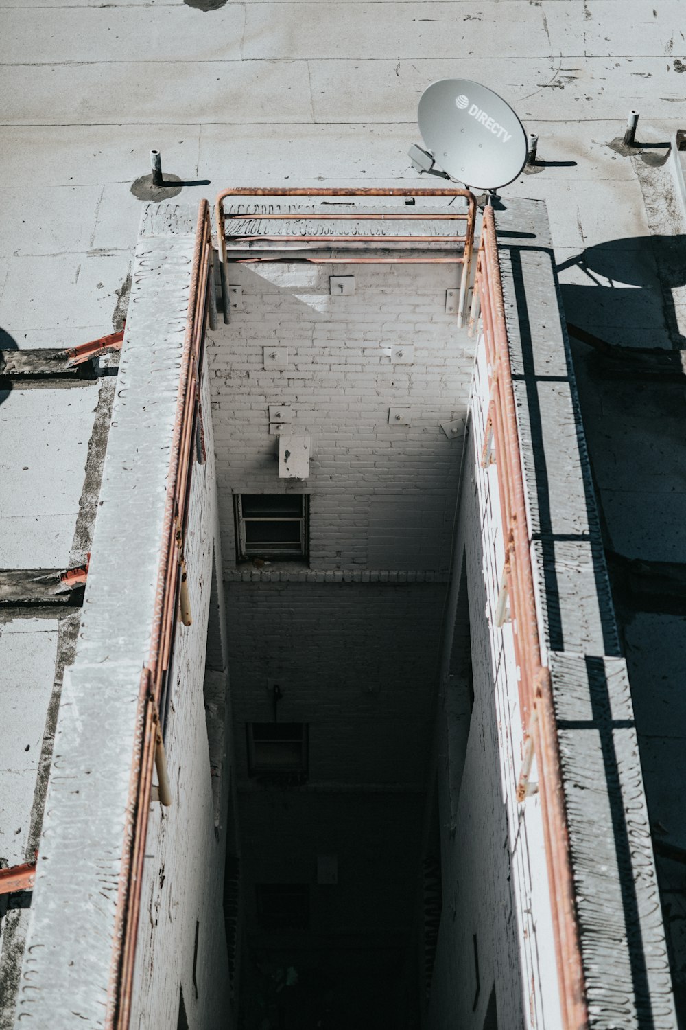 aerial photo of gray Direct TV parabolic antenna on brown steel rail during daytime