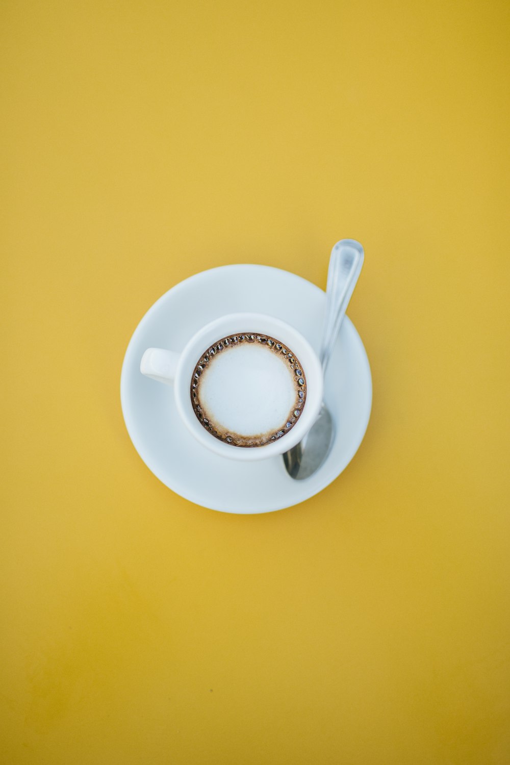 filled white teacup on saucer with teaspoon