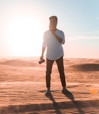 man wearing white elbow-sleeved shirt standing on dessert during daytime