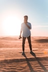 man wearing white elbow-sleeved shirt standing on dessert during daytime