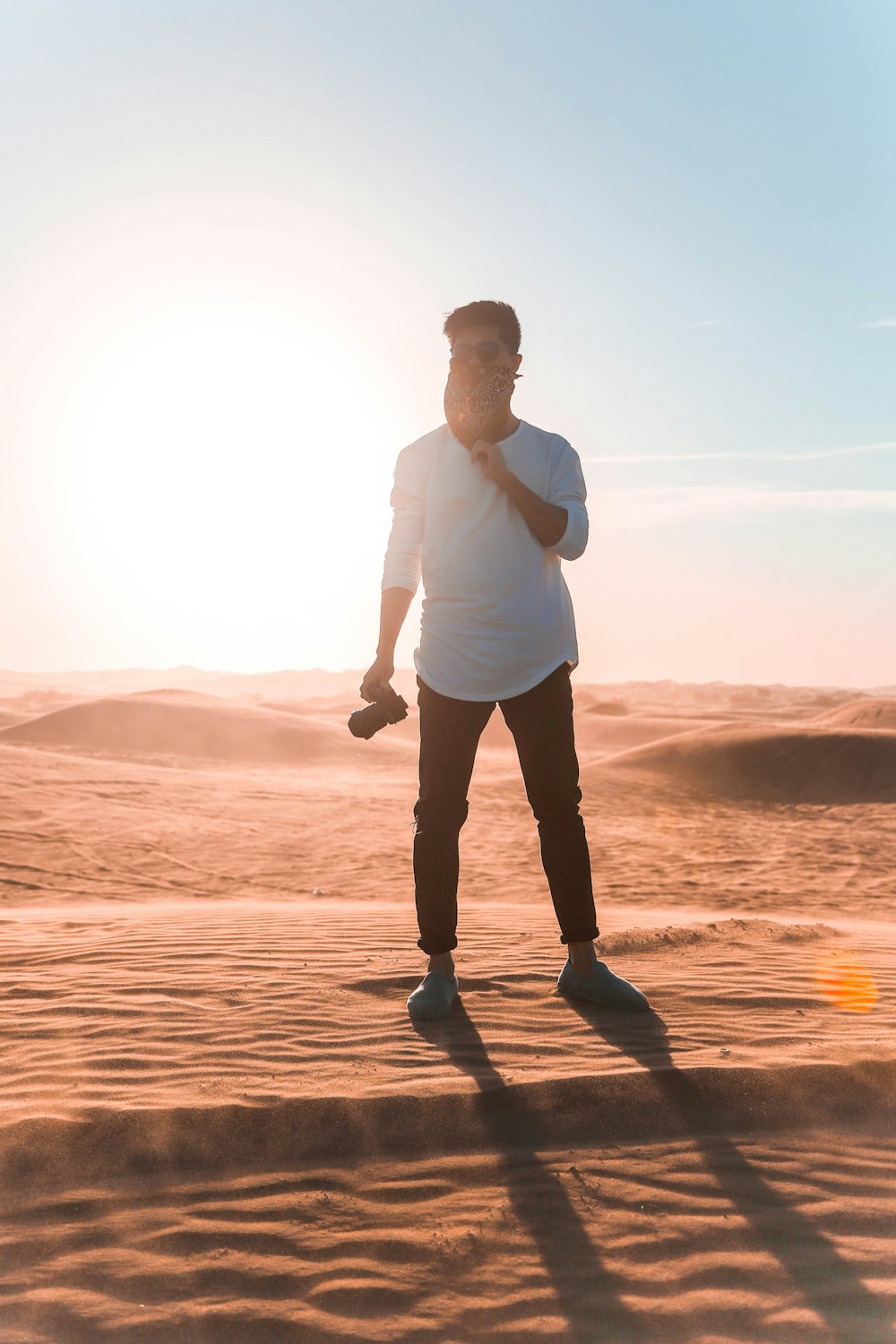 man wearing white elbow-sleeved shirt standing on dessert during daytime