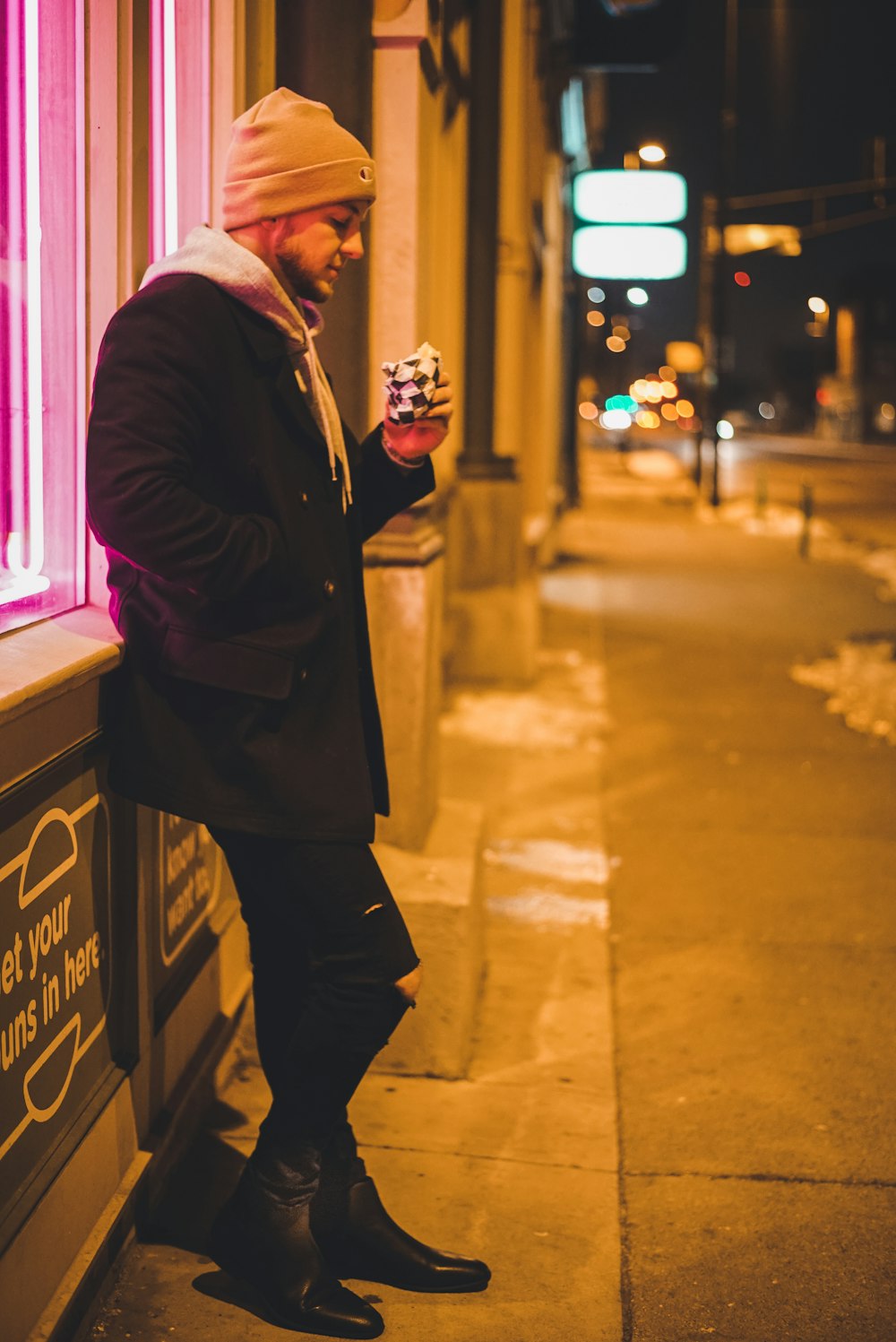 man leaning on wall while holding pack during night