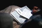 person holding black pen and writing on white notebook