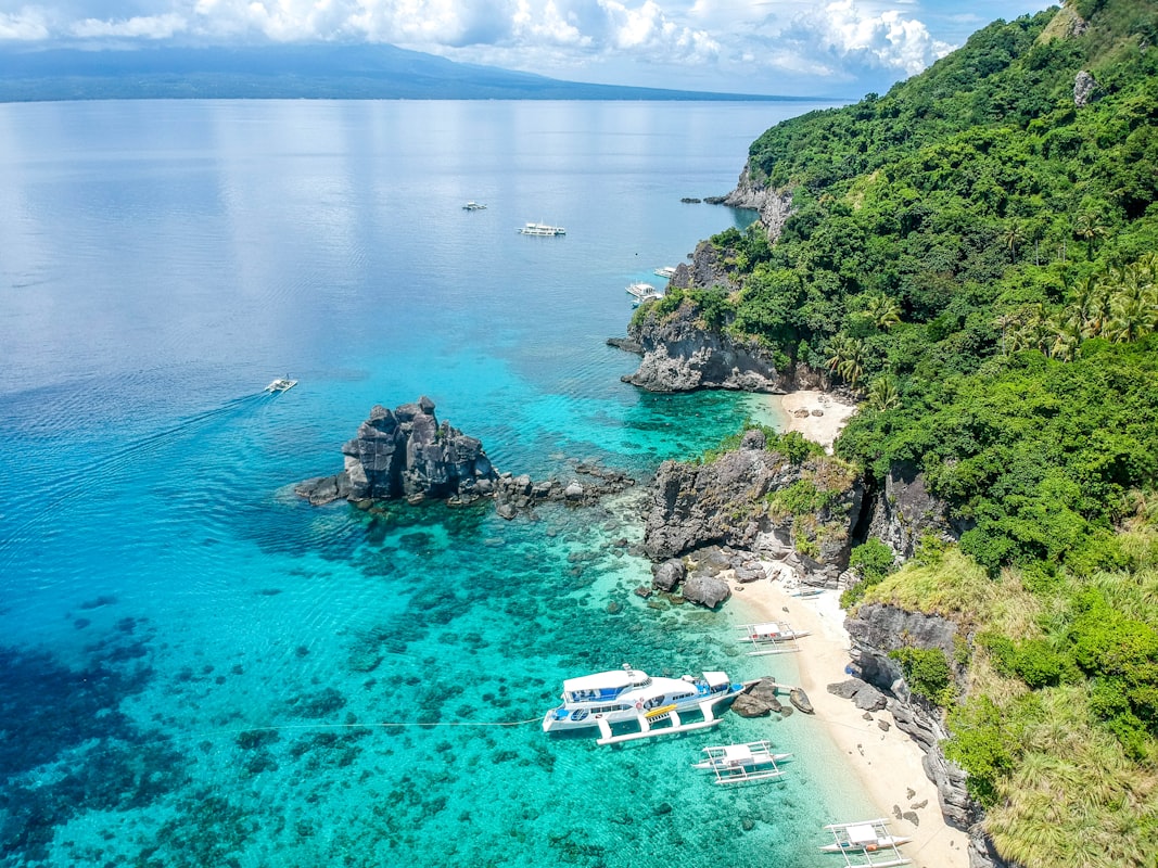 Aerial photograph of a large yacht anchored near a tropical coastline with turquoise water
