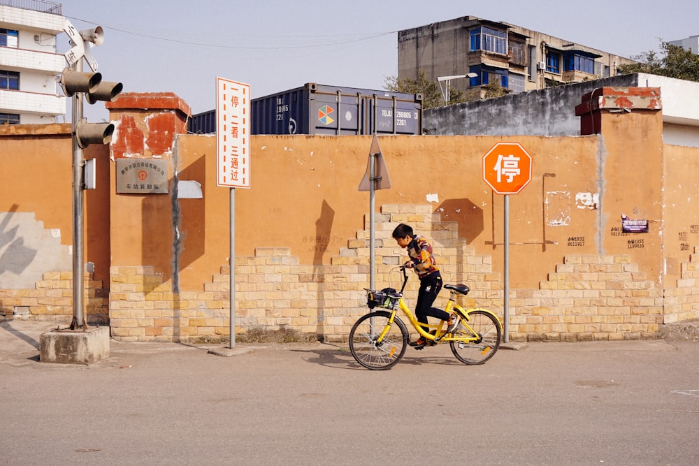 man riding bicycle beside wall