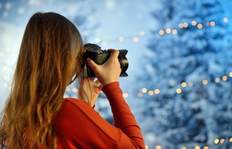 woman wearing red long-sleeved top holding camera