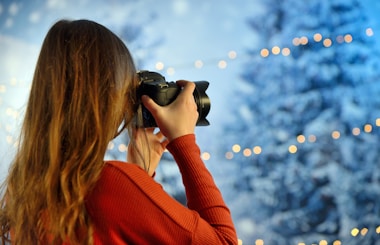 woman wearing red long-sleeved top holding camera