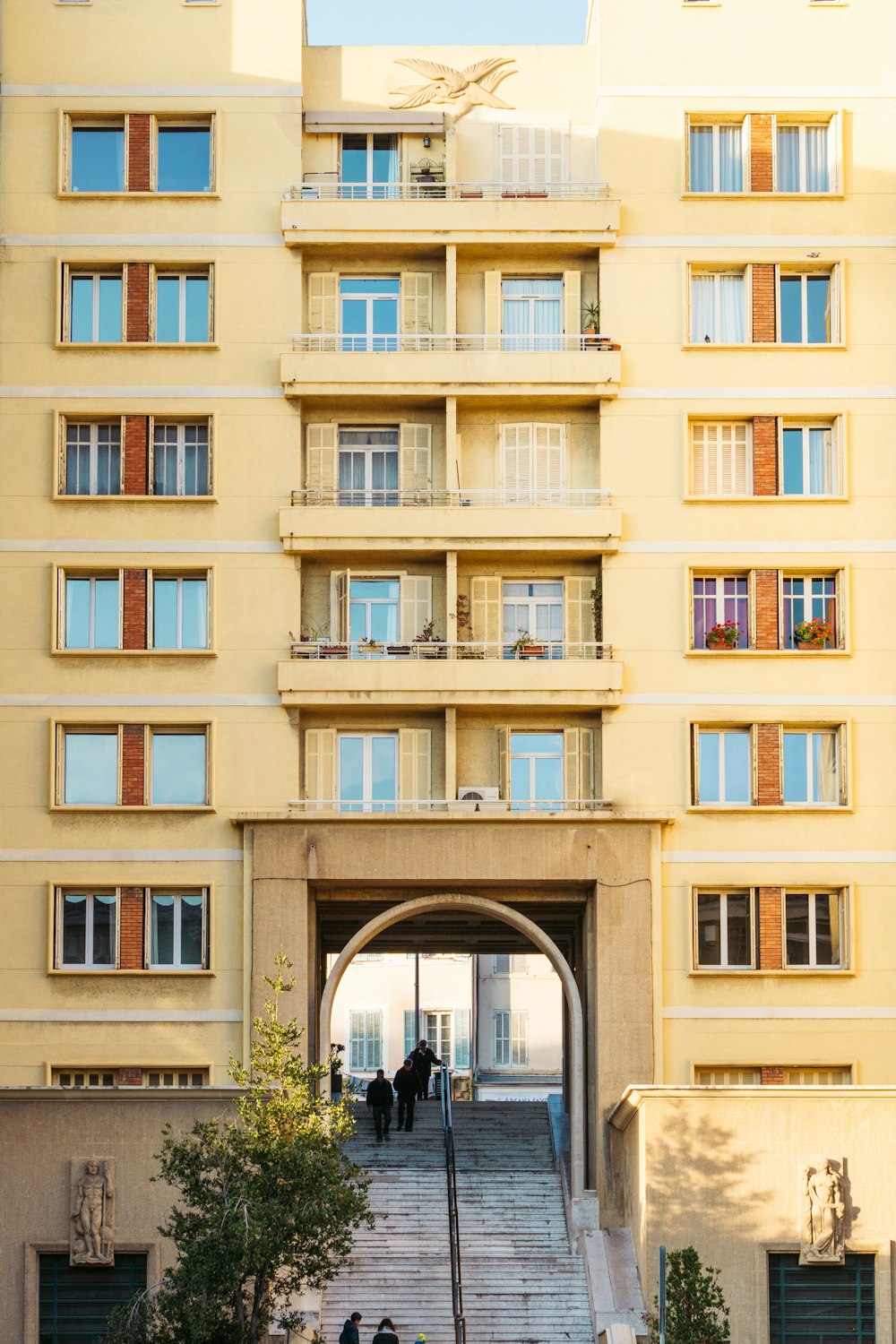 Menschen auf Treppen unter beigefarbenem Betongebäude