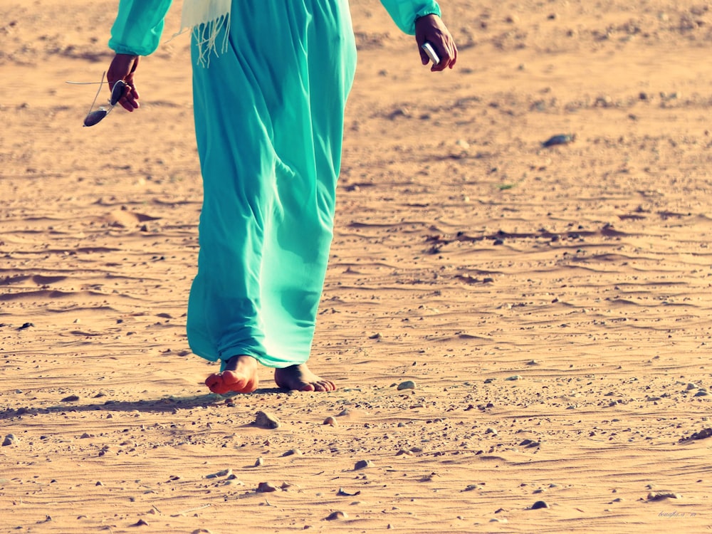 a woman in a blue dress walking in the desert