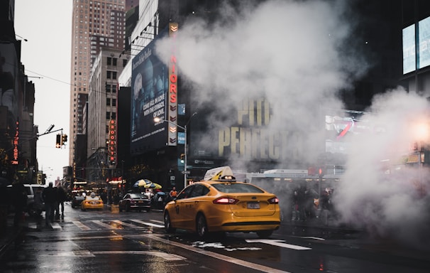 yellow taxi sedan on gray concrete street passed through white smokes near walking lane