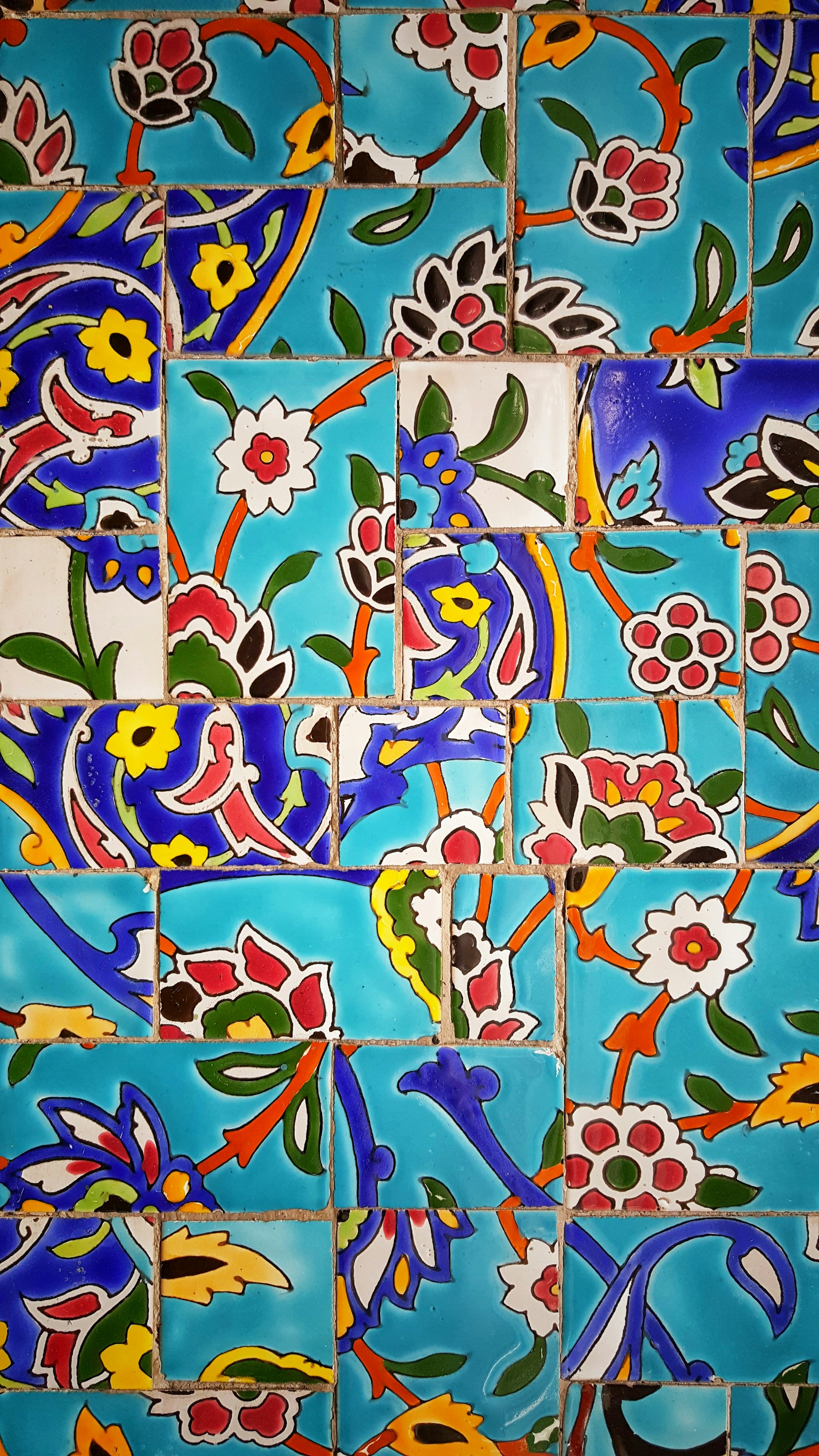 A tiled wall with unmatched flower tiles