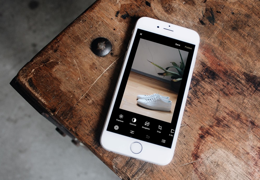 silver iPhone 6 displaying pair of white sneakers