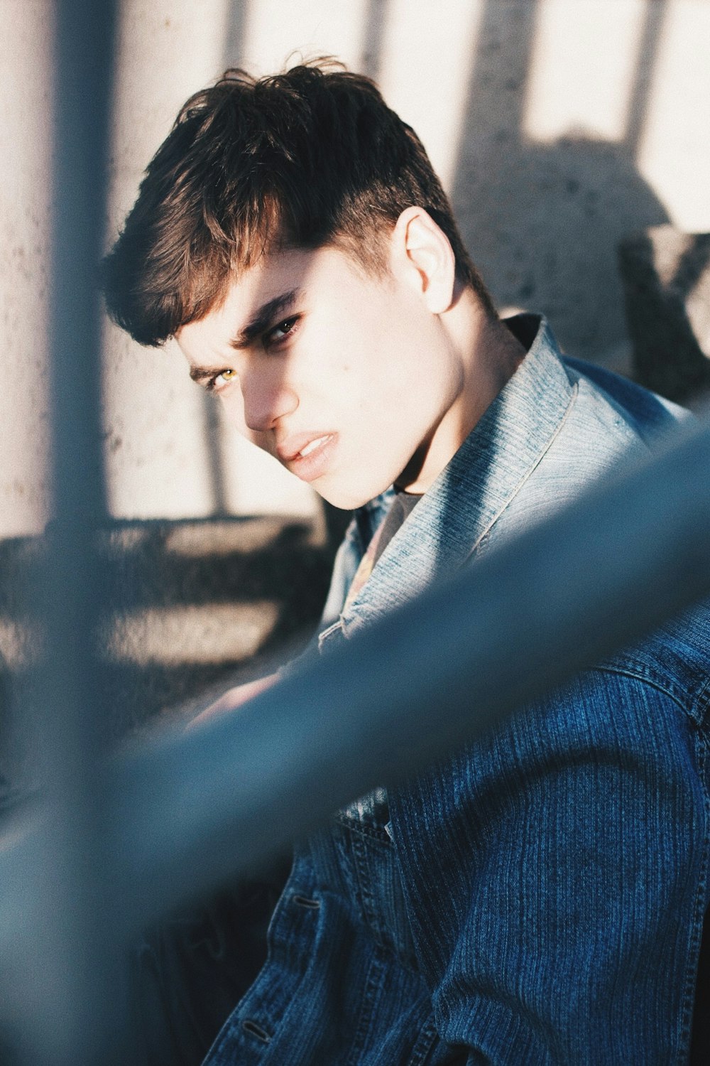 man in blue denim jacket sitting near gray steel frame