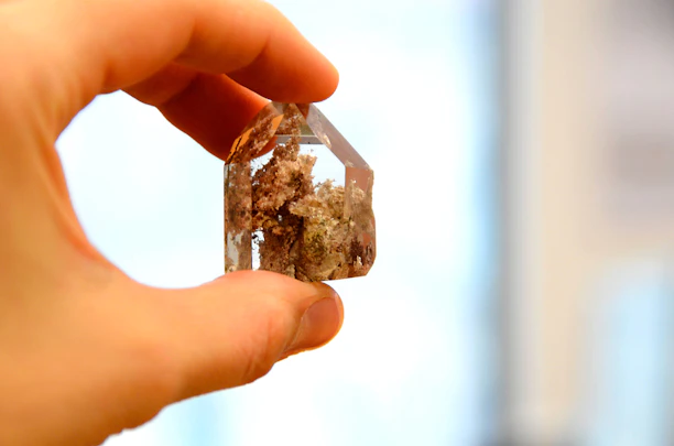 Close-up of hands carefully holding a sparkling quartz crystal under natural light.