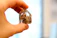 Close-up of a hand gently holding a staurolite fairy cross crystal against a soft natural background.
