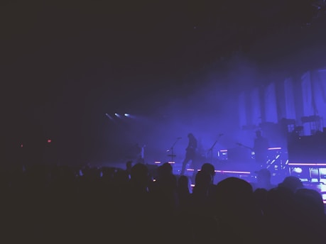 A moody live concert scene with a band performing under dim stage lights.