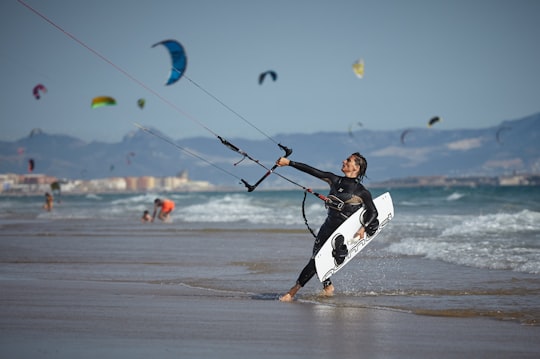 woman holding wakeboard on beach in Tarifa Spain