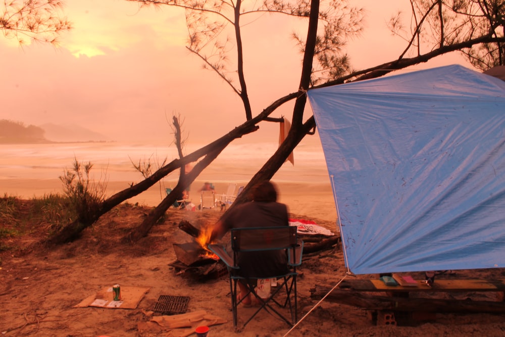 person sitting on chair near tent and body of water