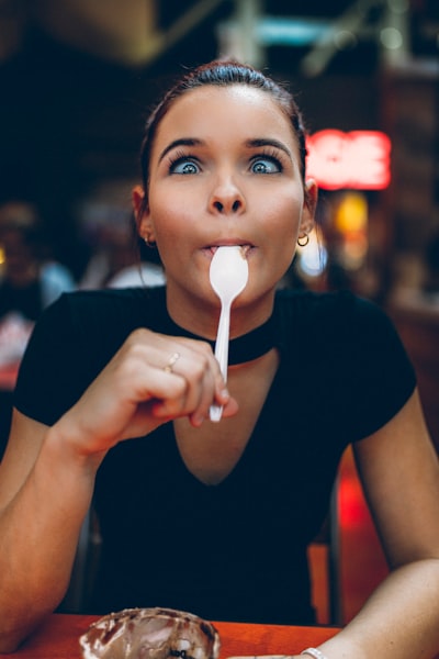 woman holding spoon on tongue