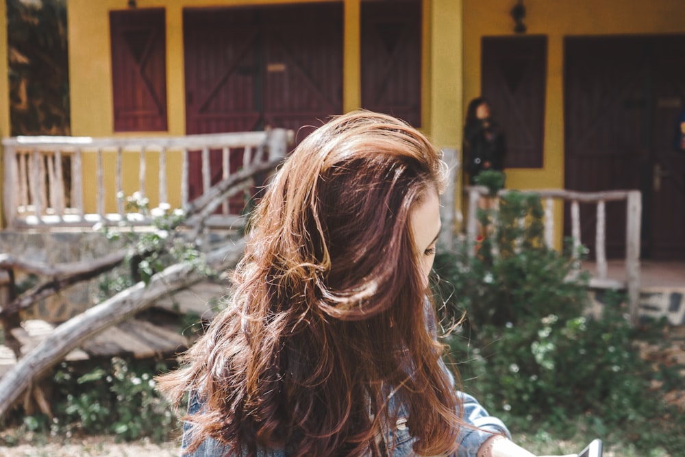 femme aux cheveux bruns debout devant un bâtiment jaune pendant la journée