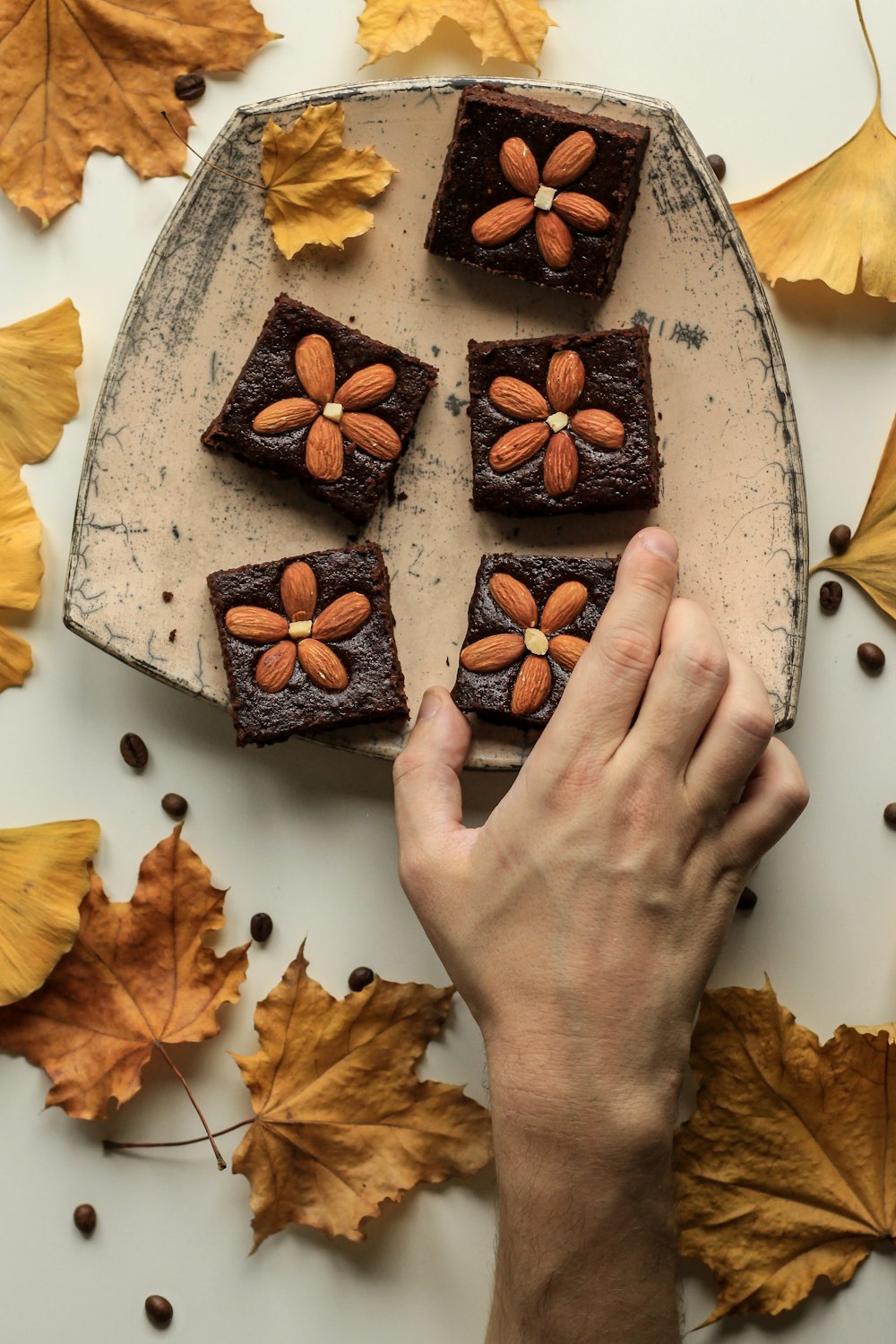 person holding almond topping cookies