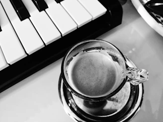 Close-up of hands typing on a keyboard with a cup of coffee nearby, warm lighting.