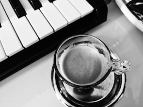 A close-up of hands typing on a keyboard with a coffee cup.