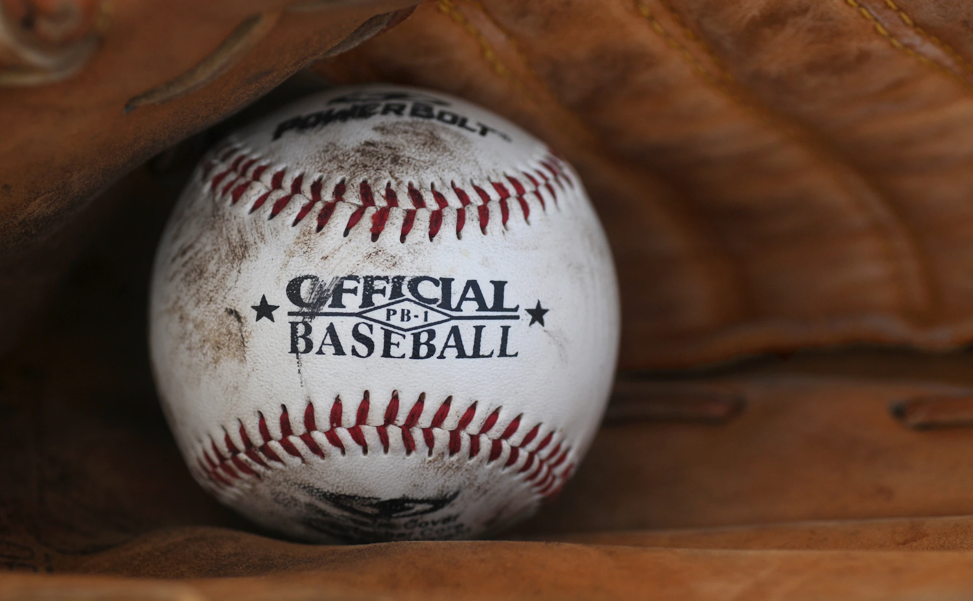 dirt covered Official Baseball ball in person's baseball mitts