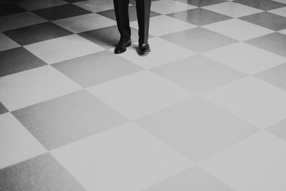 Persona in piedi sul pavimento a scacchi grigio e nero