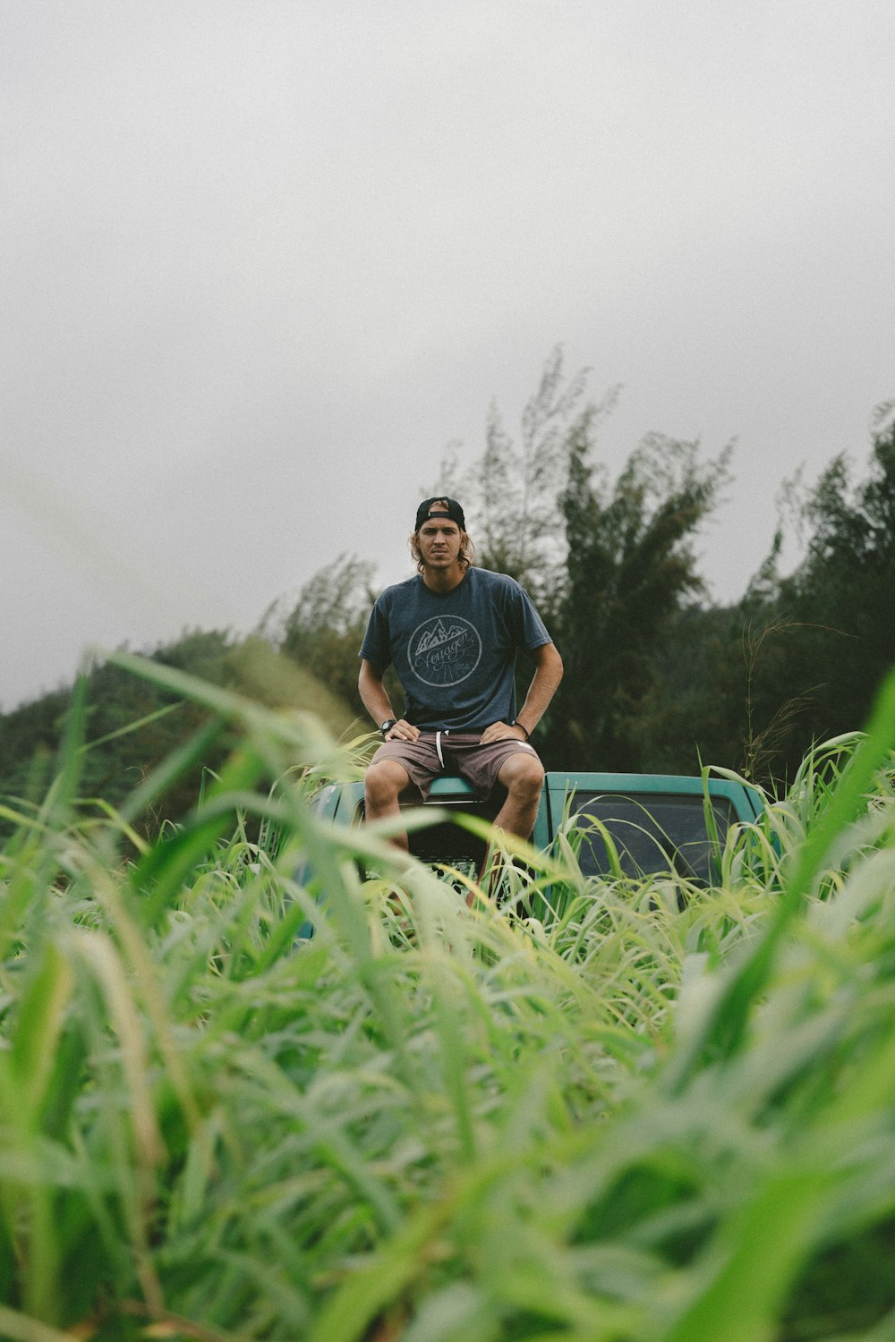 man in black crew-neck t-shirt sitting on green vehicle roof