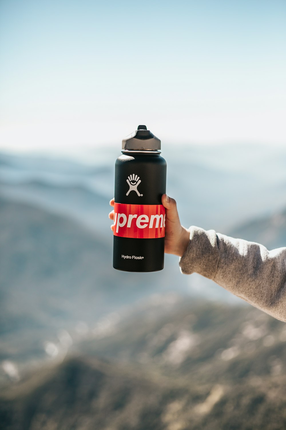 Person mit schwarz-roter Supreme-Sportflasche