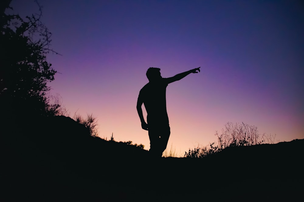 man in silhouette photo standing on cliff