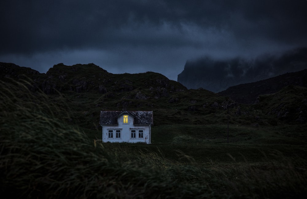 casa blanca y marrón en la montaña bajo nubes negras