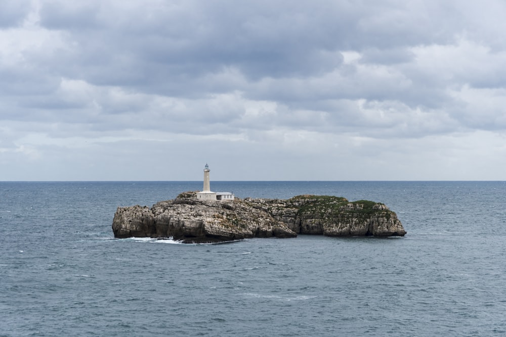 lighthouse on islet under cloudy skies