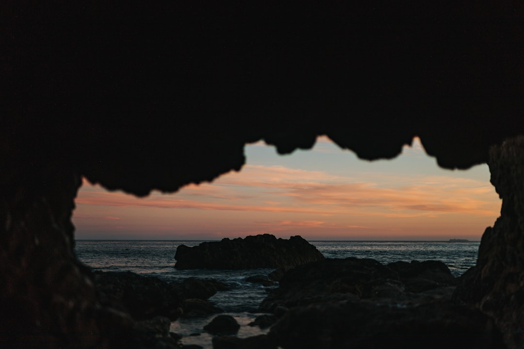 view of ocean from a cave during sunset