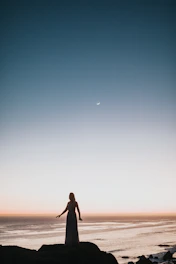 A contemplative man standing on a rugged coastline at dusk, symbolizing resilience and new beginnings.