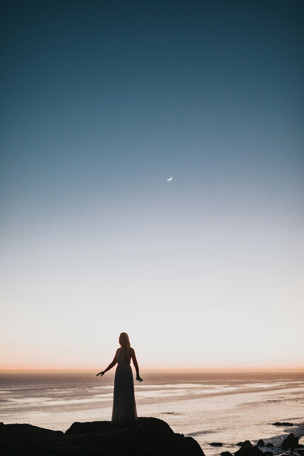 woman in dress standing near body of water