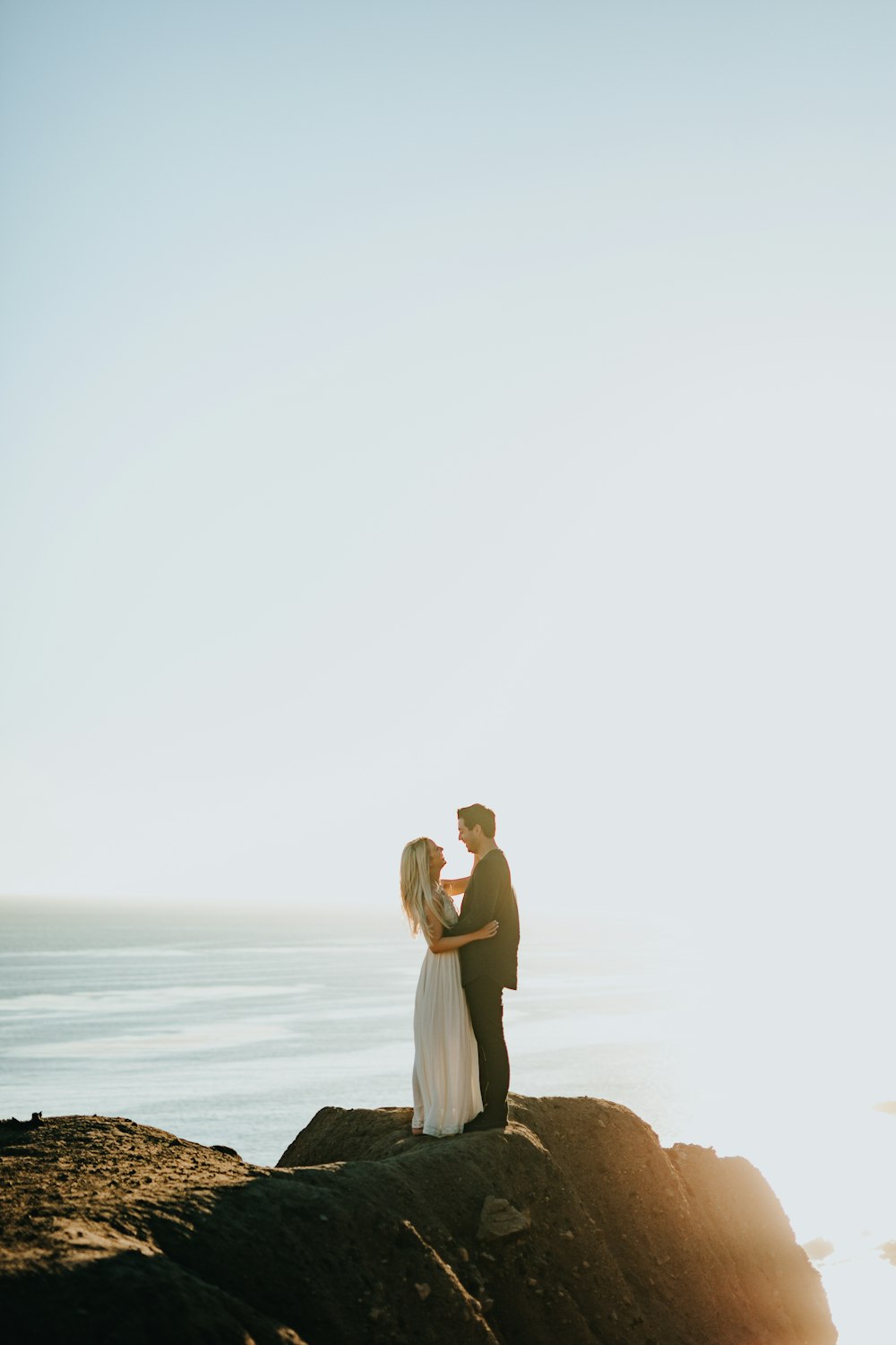 woman and man standing on brown rock formation during daytime