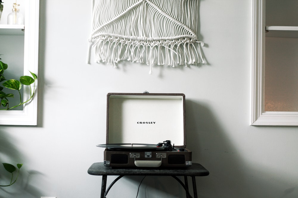 platine vinyle Crosley noire sur table noire près du mur blanc