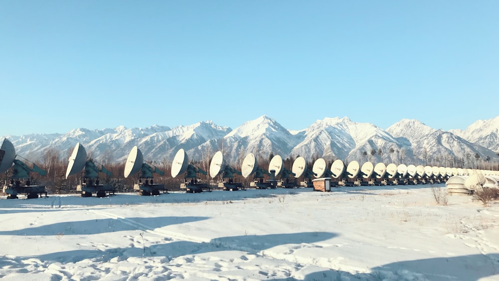 white satellites on snowfield near mountains and trees during daytime