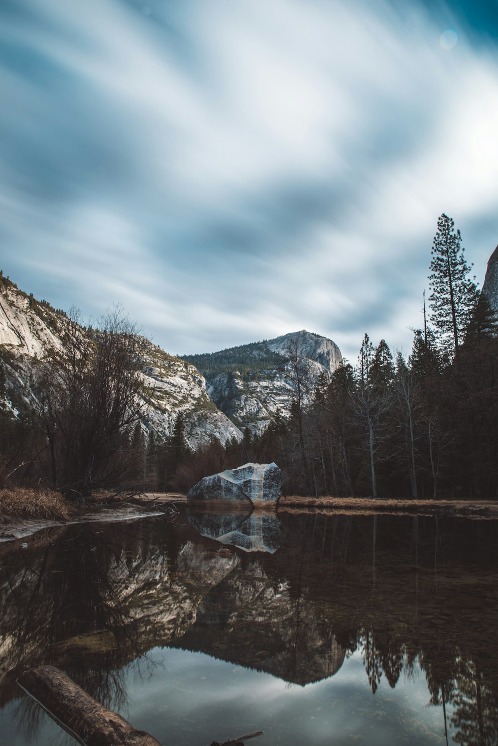 mirror photography of mountain and trees under white and blue skies