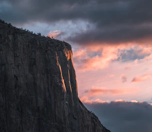 A mysterious ancient Mesopotamian cliff bathed in golden-orange light at dusk.