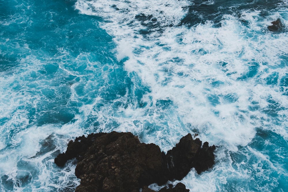 aerial photography of black rock formations near seawaves