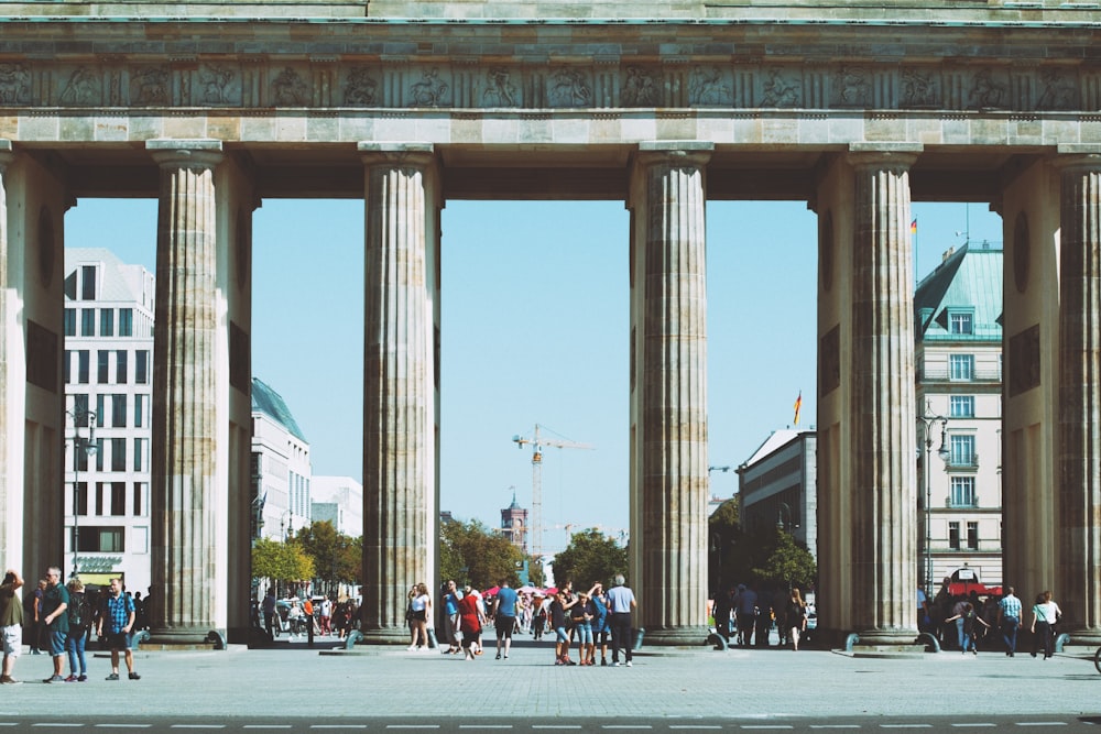 people under brown building with 6 pillars